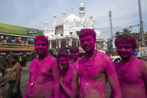 Pèlerins très souriants devant la mosquée. Visages colorés avec de la poudre Magenta